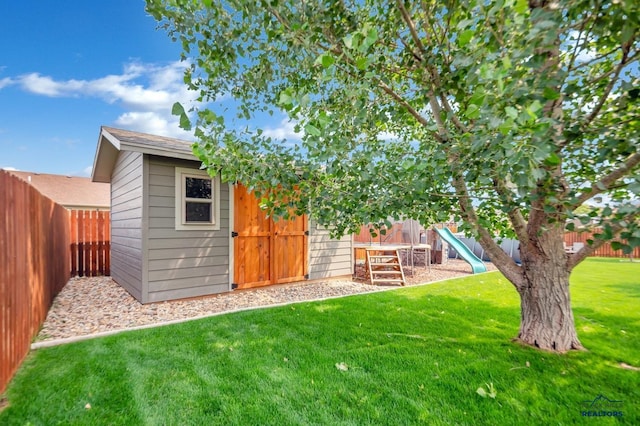 view of yard with a fenced backyard, a playground, and an outbuilding