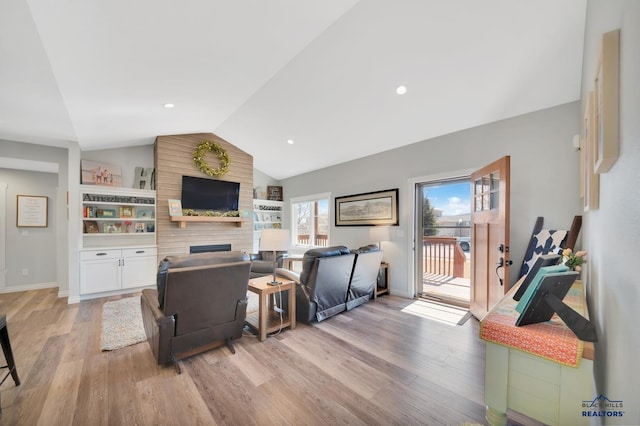 living room featuring lofted ceiling, a large fireplace, light wood-style floors, and recessed lighting