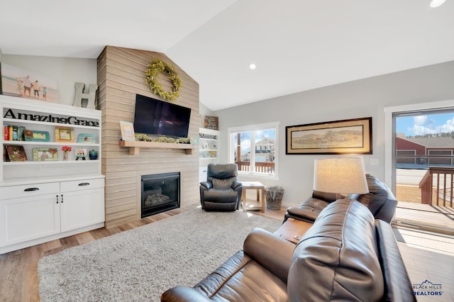 living room featuring lofted ceiling, light wood finished floors, and a fireplace