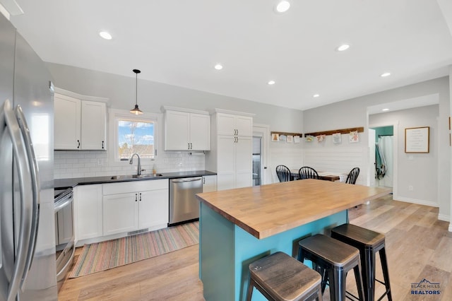 kitchen featuring light wood finished floors, visible vents, a breakfast bar, stainless steel appliances, and a sink