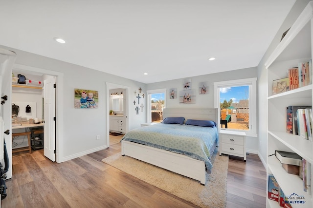 bedroom with recessed lighting, ensuite bath, baseboards, and wood finished floors