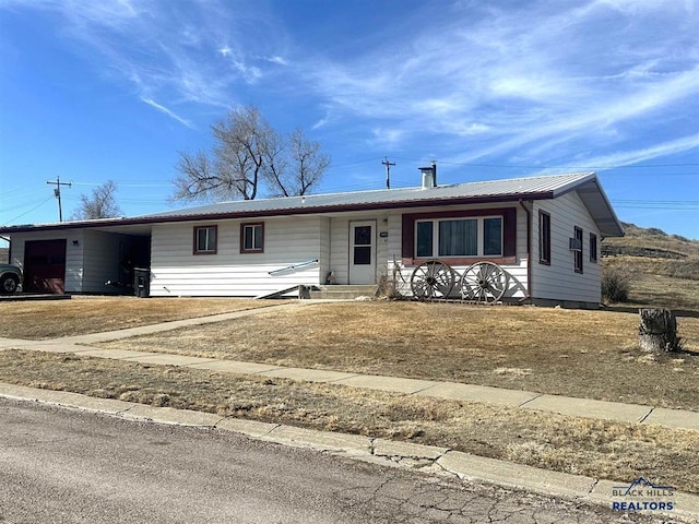 ranch-style house with a carport, metal roof, covered porch, and driveway