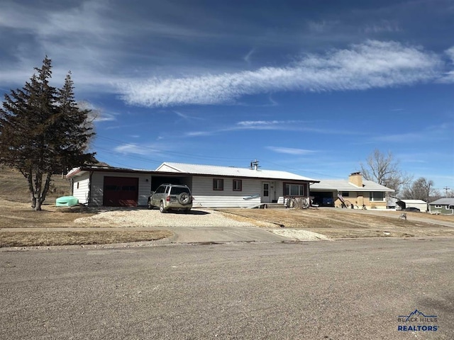 ranch-style home featuring gravel driveway and an attached garage