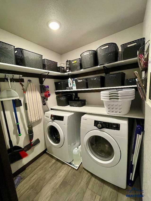 clothes washing area featuring laundry area, a textured ceiling, separate washer and dryer, and wood finished floors