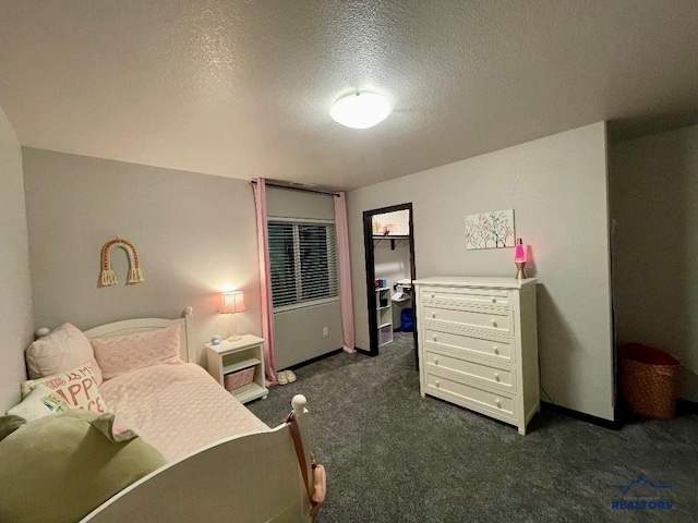 bedroom featuring a textured ceiling and dark carpet