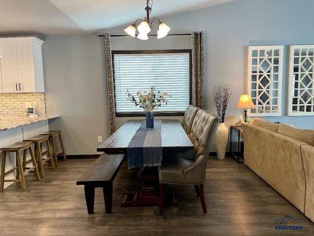 dining room with lofted ceiling, dark wood-type flooring, baseboards, and an inviting chandelier