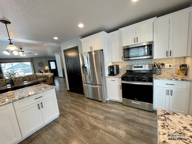 kitchen featuring decorative backsplash, appliances with stainless steel finishes, open floor plan, white cabinets, and wood finished floors