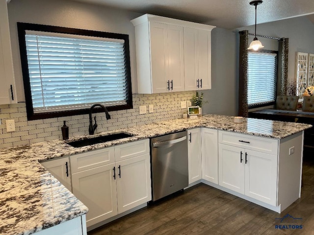 kitchen featuring dark wood-style floors, stainless steel dishwasher, white cabinetry, a sink, and a peninsula