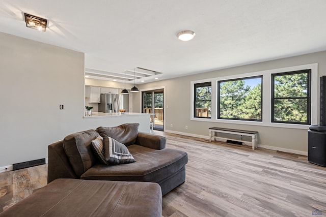 living area with light wood finished floors, visible vents, and baseboards