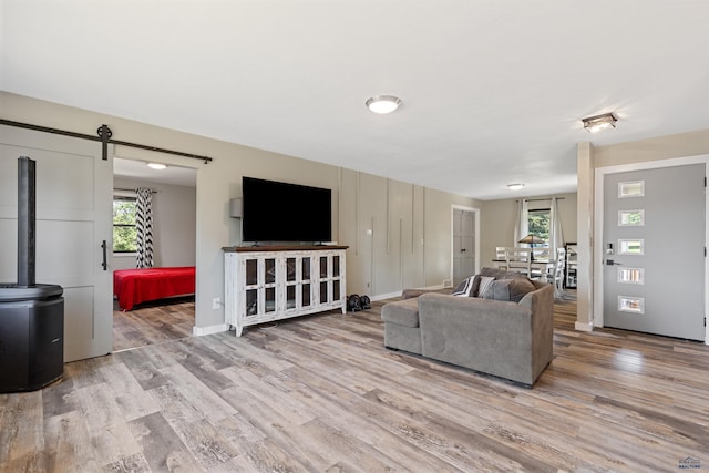 living area featuring plenty of natural light, a barn door, baseboards, and wood finished floors