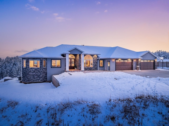 view of front of house featuring stone siding, fence, and an attached garage