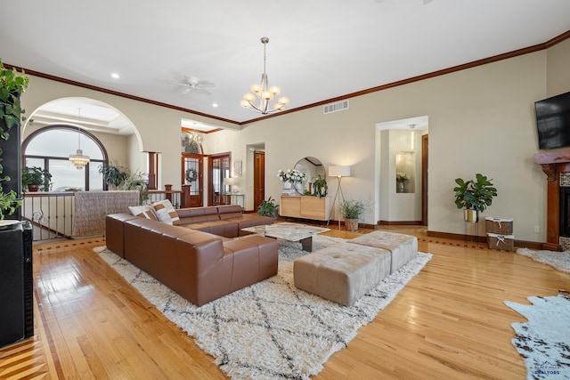 living area featuring light wood-type flooring, a glass covered fireplace, visible vents, and baseboards