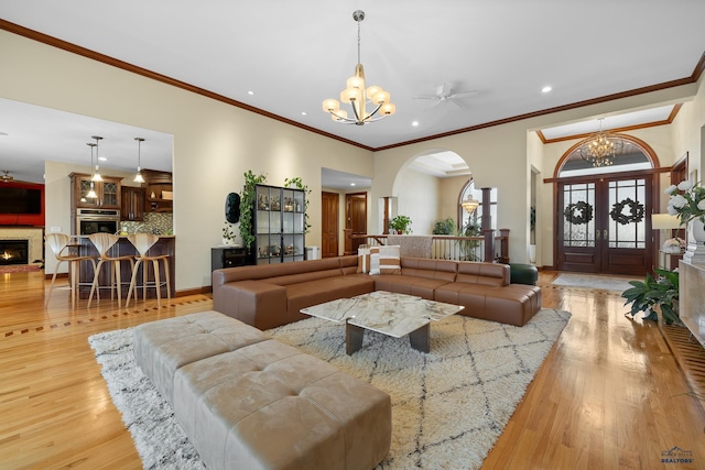 living area featuring a lit fireplace, recessed lighting, wood finished floors, and an inviting chandelier