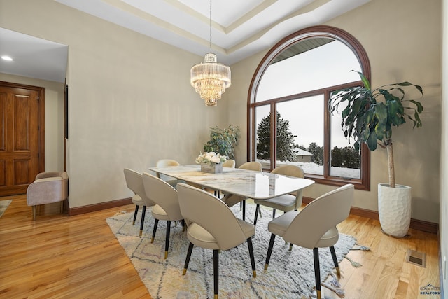 dining area with light wood finished floors, baseboards, visible vents, and a chandelier