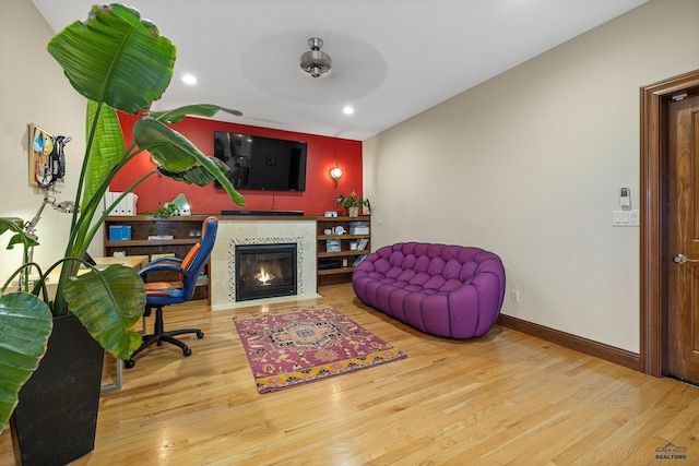 living room featuring recessed lighting, a fireplace, wood finished floors, and baseboards