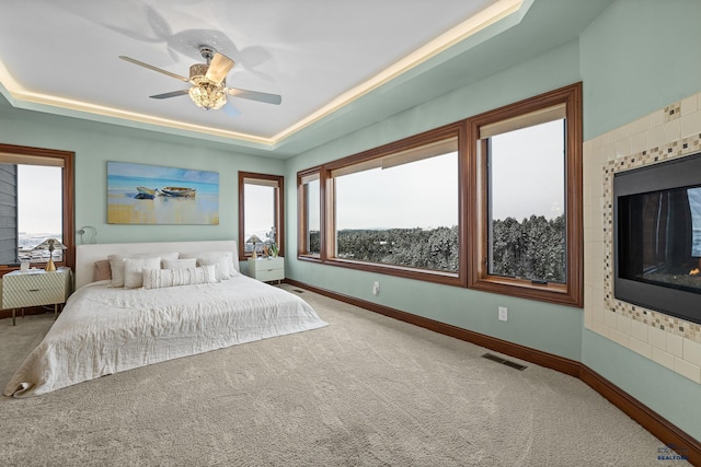 bedroom with a tray ceiling, carpet, visible vents, and baseboards