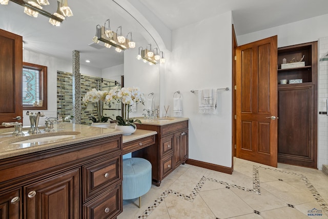 bathroom featuring a stall shower, two vanities, a sink, and baseboards