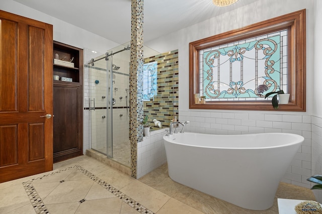 bathroom featuring a stall shower, a soaking tub, tile walls, and tile patterned floors