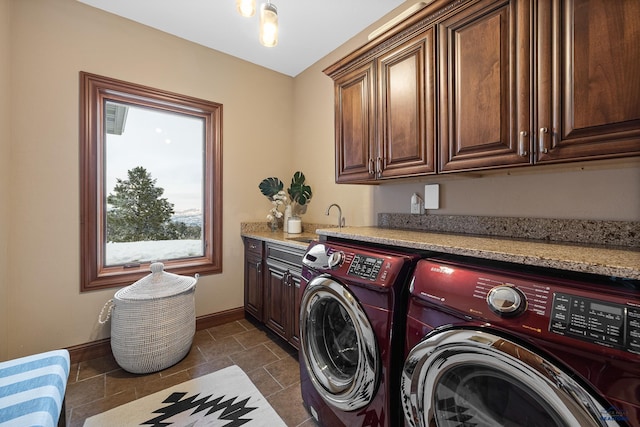 washroom with cabinet space, stone finish floor, a sink, separate washer and dryer, and baseboards