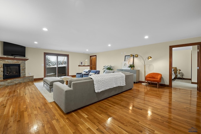 living room with light wood finished floors, recessed lighting, baseboards, and a stone fireplace