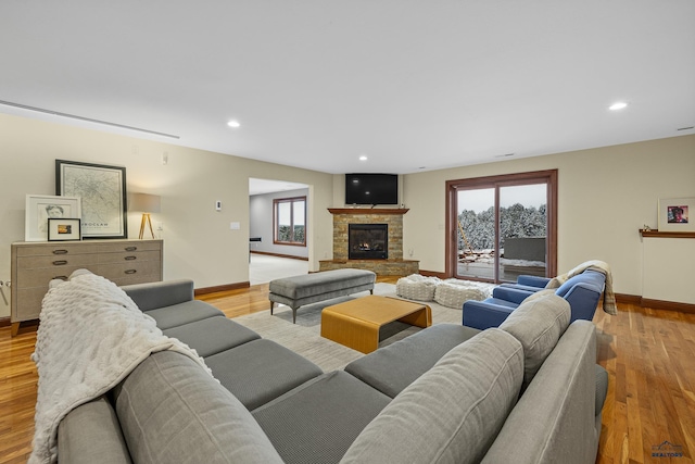 living room with light wood-type flooring, a fireplace, baseboards, and recessed lighting