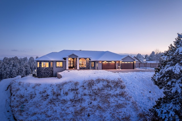 view of front of house featuring stone siding, fence, and an attached garage