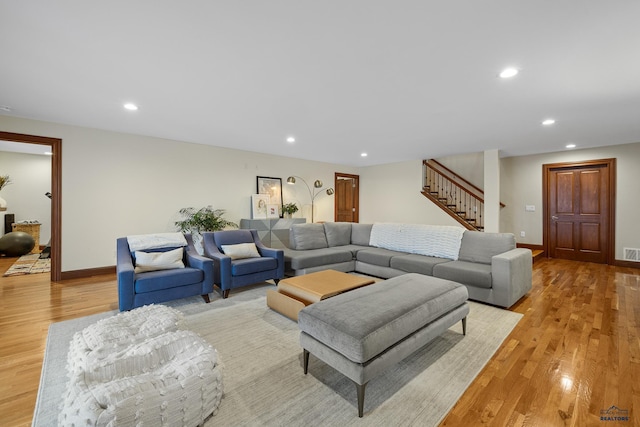 living room featuring light wood-style floors, recessed lighting, and stairs