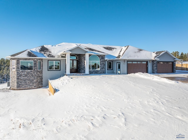 view of front of property featuring an attached garage, stone siding, and stucco siding