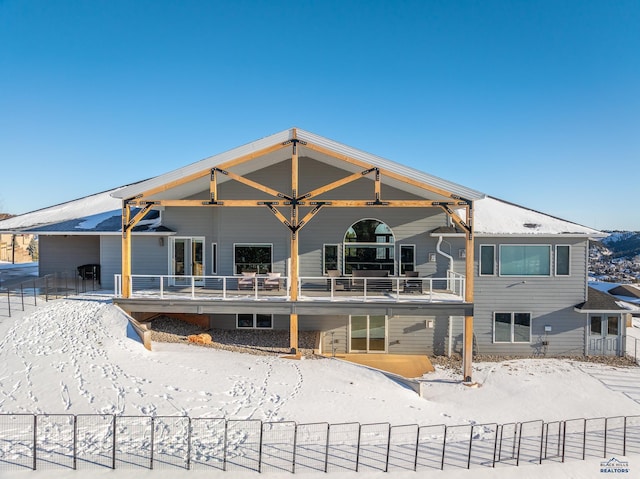 snow covered property featuring a ceiling fan, fence, and a balcony