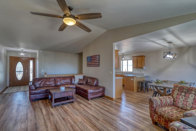 living room with vaulted ceiling, a ceiling fan, light wood-style flooring, and baseboards