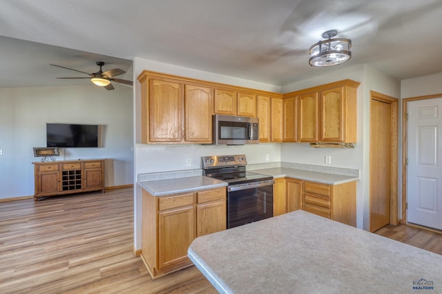 kitchen featuring light wood-type flooring, appliances with stainless steel finishes, light countertops, and open floor plan