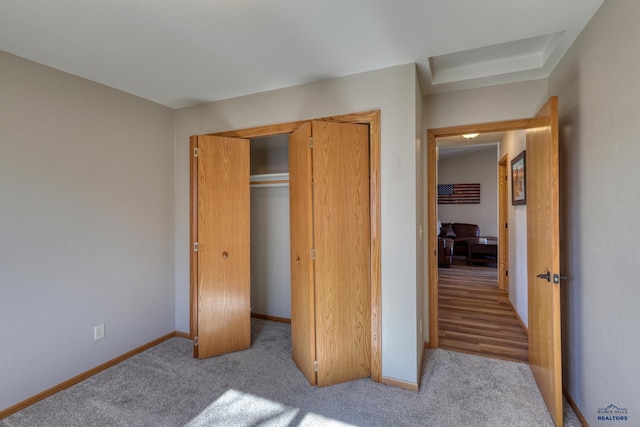 unfurnished bedroom featuring carpet floors, baseboards, and a closet