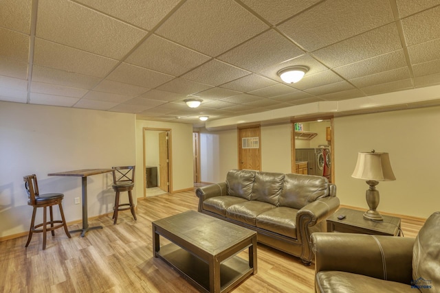 living area featuring baseboards, a drop ceiling, visible vents, and light wood finished floors