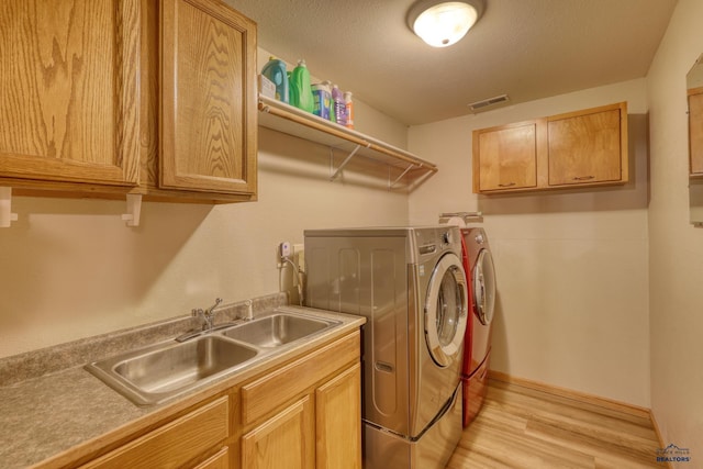 clothes washing area with separate washer and dryer, a sink, visible vents, light wood-type flooring, and cabinet space