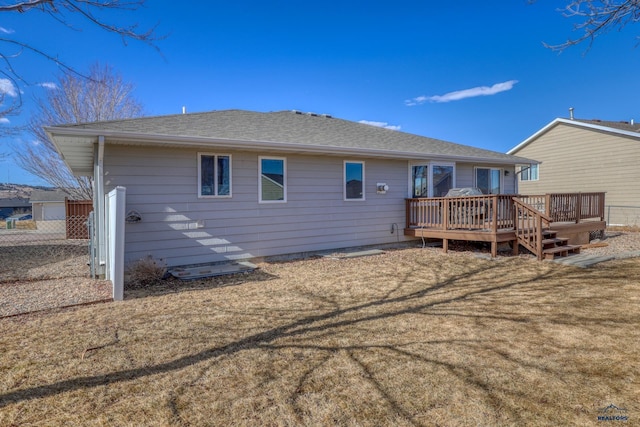 rear view of property featuring a shingled roof, a deck, and a yard