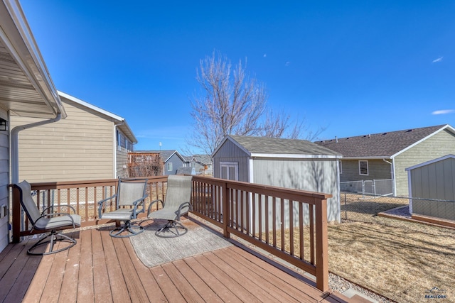 wooden deck featuring a shed, a residential view, fence, and an outdoor structure