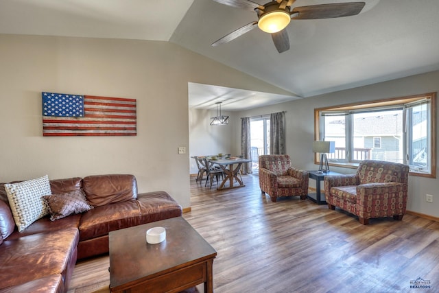 living area with baseboards, a ceiling fan, vaulted ceiling, and wood finished floors