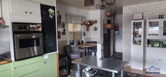 1001 E St, Edgemont, SD 57735 - kitchen with stainless steel oven, brick wall, and wood finished floors
