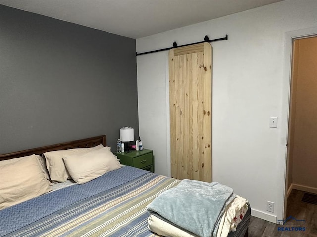 1001 E St, Edgemont, SD 57735 - bedroom with a barn door, visible vents, baseboards, and wood finished floors