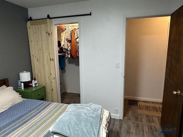 1001 E St, Edgemont, SD 57735 - bedroom with a barn door, baseboards, wood finished floors, a walk in closet, and a closet