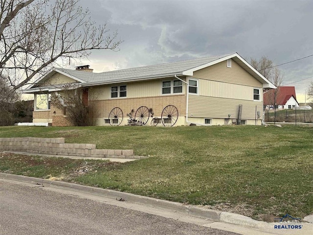 ranch-style home featuring a front lawn, a chimney, and brick siding