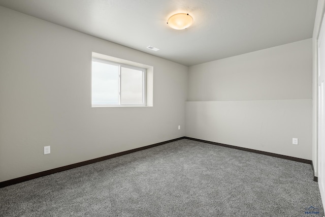 spare room with carpet floors, visible vents, and baseboards