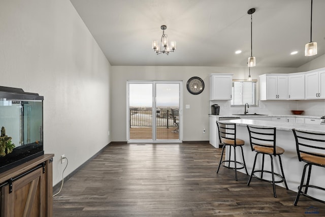 kitchen featuring dark wood-style flooring, a kitchen bar, white cabinets, and decorative backsplash