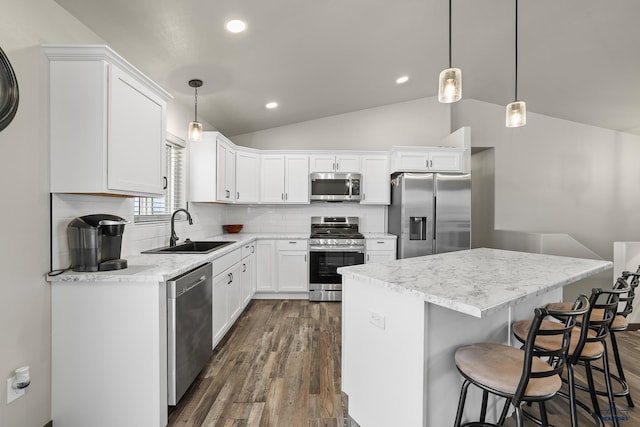 kitchen featuring a center island, stainless steel appliances, lofted ceiling, tasteful backsplash, and a sink