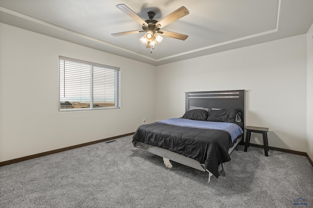 carpeted bedroom featuring a tray ceiling, visible vents, and baseboards