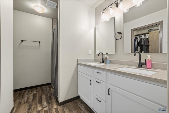 full bath featuring double vanity, visible vents, a sink, and wood finished floors