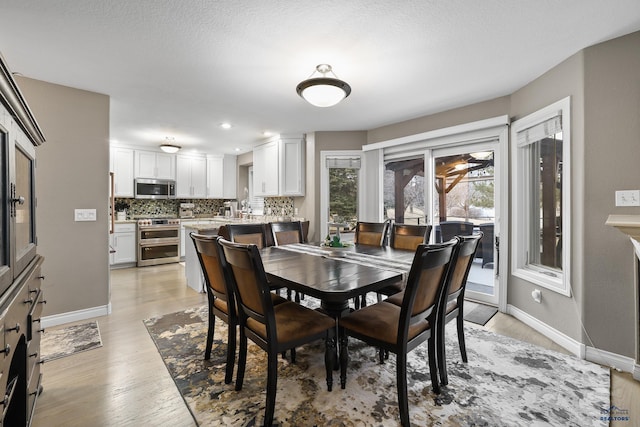 dining room with a textured ceiling, recessed lighting, light wood-style flooring, and baseboards