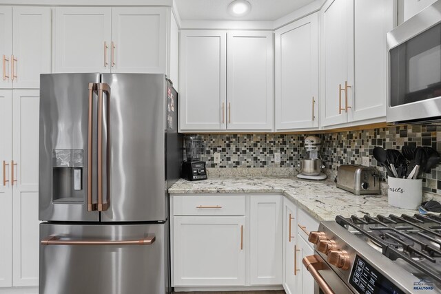 kitchen with stainless steel appliances, white cabinetry, and decorative backsplash