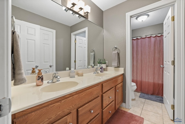 full bath featuring double vanity, a sink, toilet, and tile patterned floors