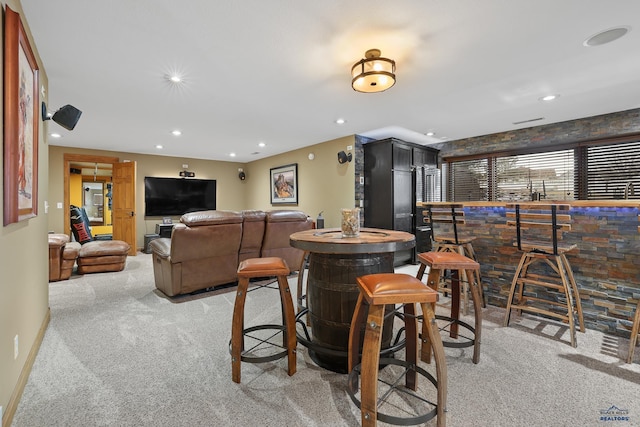 interior space featuring recessed lighting, baseboards, light colored carpet, and a bar